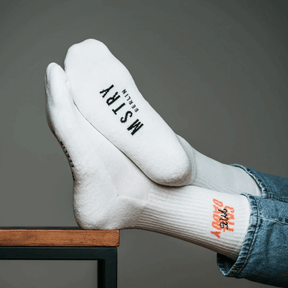 Mstry Socken Call me Daddy am Fuß, Beine liegen übereinander geschlagen auf einem Tisch