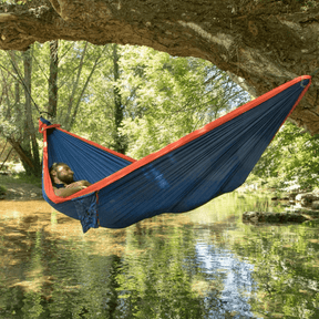 Mann liegt in einer King Size Hängematte an einem Baum, über einem See